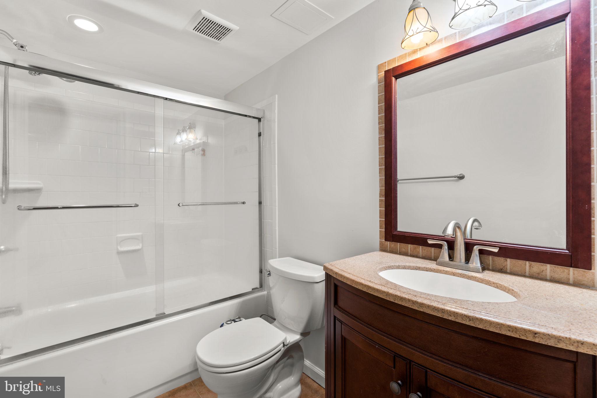 8111 Phirne Road East Glen Burnie, MD 21061 - Photo 24 of 30 a bathroom with a granite countertop sink toilet a mirror and shower