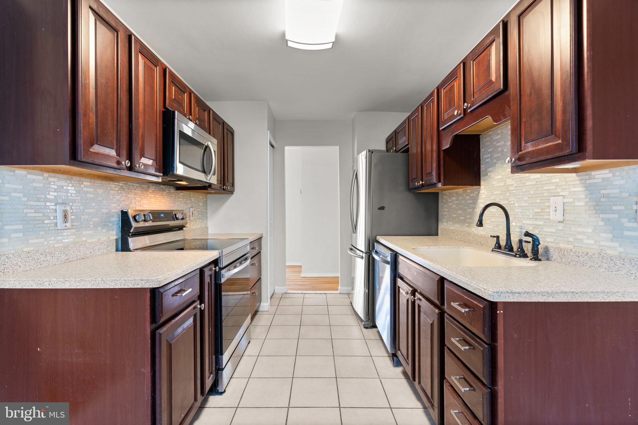 8111 Phirne Road East Glen Burnie, MD 21061 - Photo 9 of 30 a kitchen with stainless steel appliances granite countertop a sink stove and cabinets