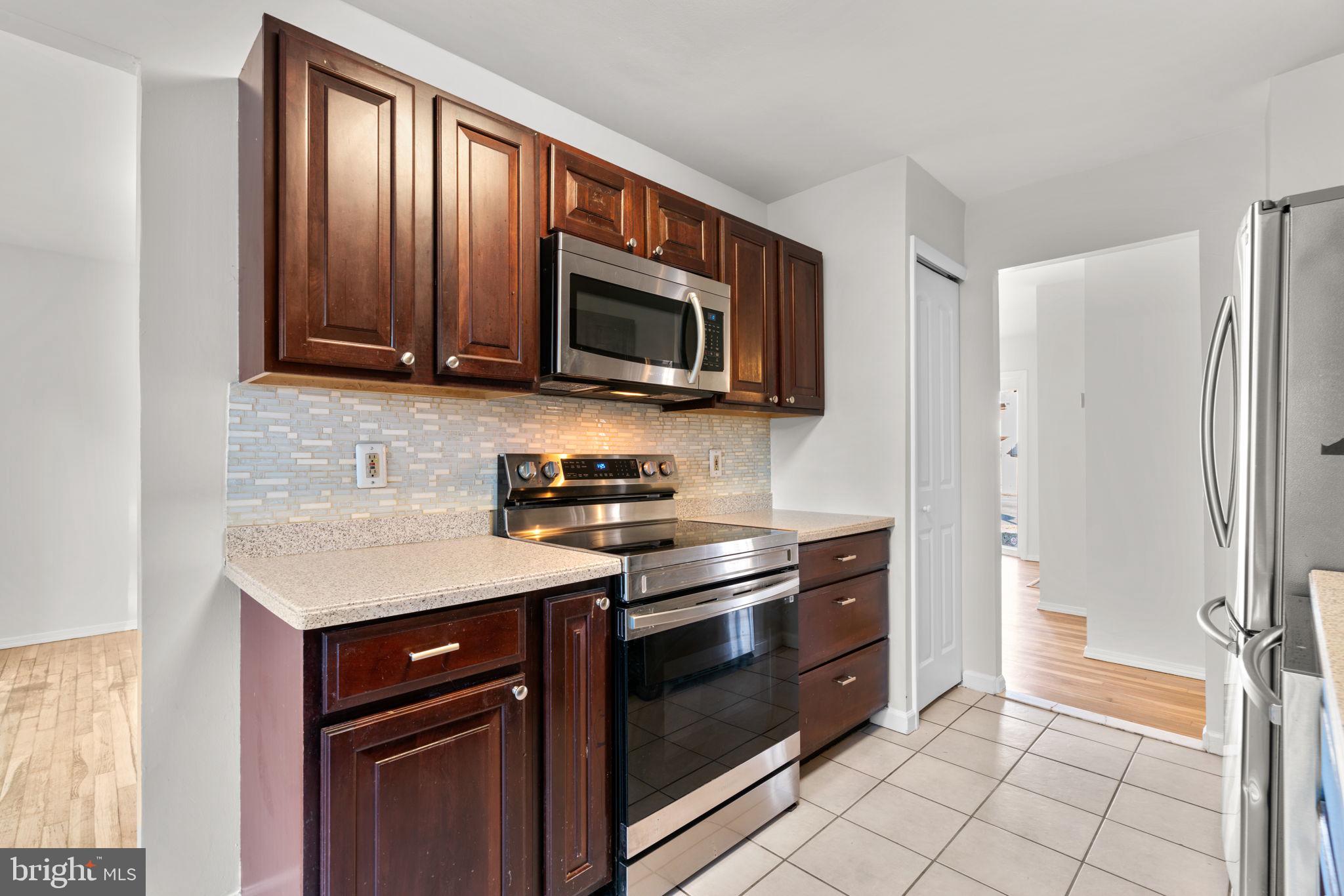 8111 Phirne Road East Glen Burnie, MD 21061 - Photo 10 of 30 a kitchen with granite countertop a stove and a microwave