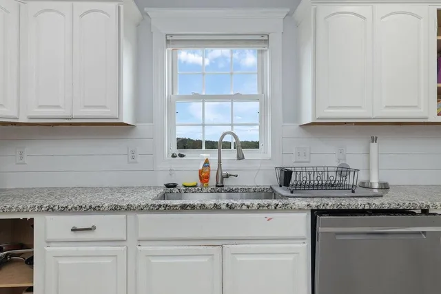 a kitchen with granite countertop white cabinets and a sink