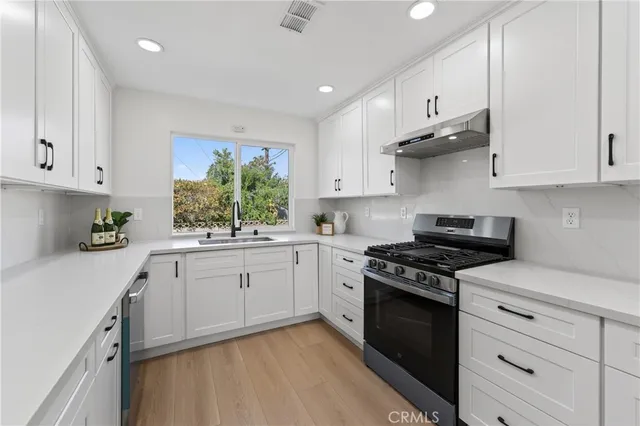 a kitchen with stainless steel appliances white cabinets and a stove top oven