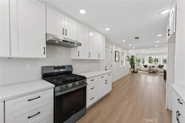 a kitchen with stainless steel appliances a stove a sink cabinets and wooden floor