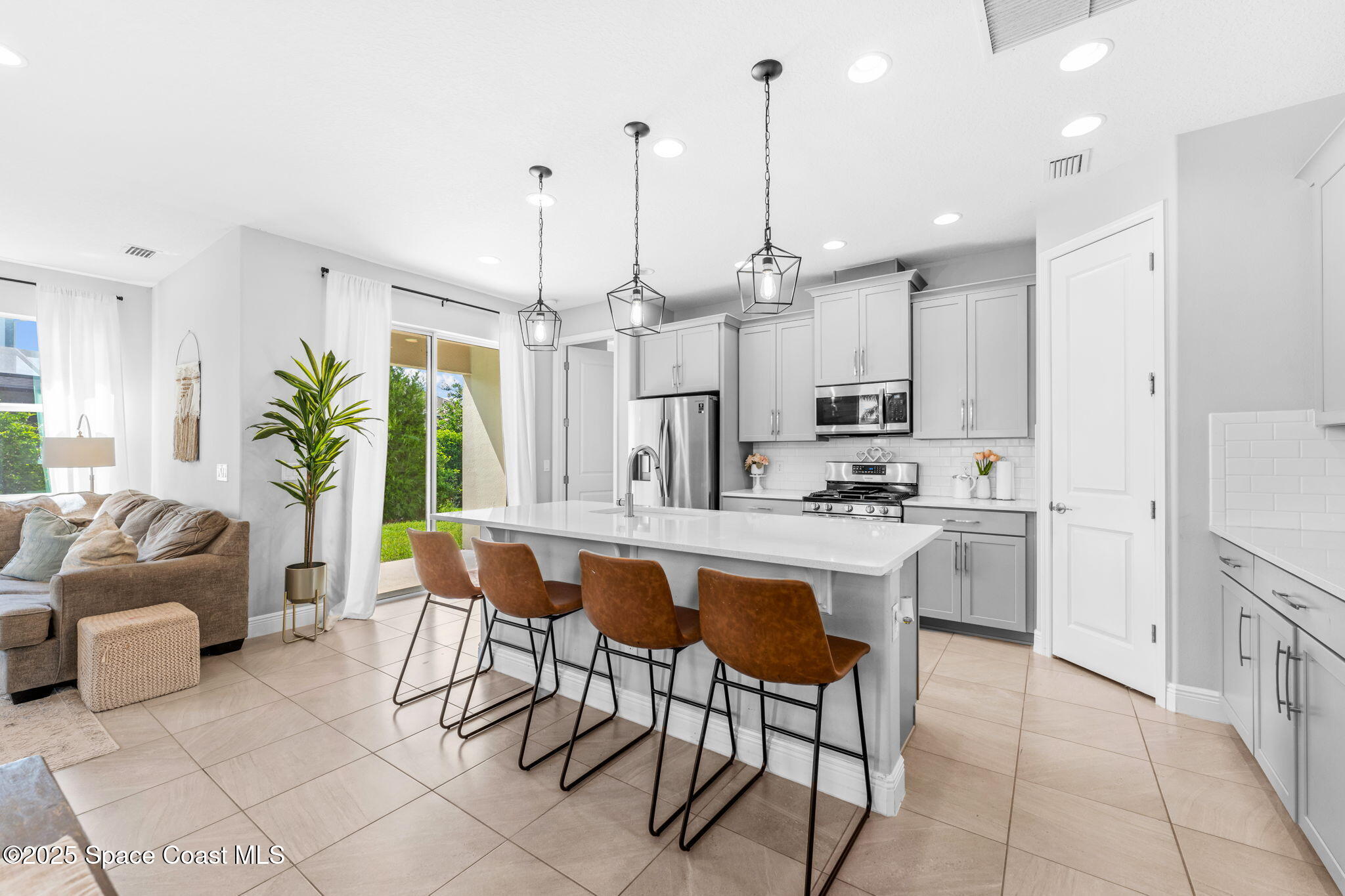 3089 Ribbon Grass Drive Melbourne, FL 32940 - Photo 10 of 57 a kitchen with stainless steel appliances kitchen island a table and chairs in it