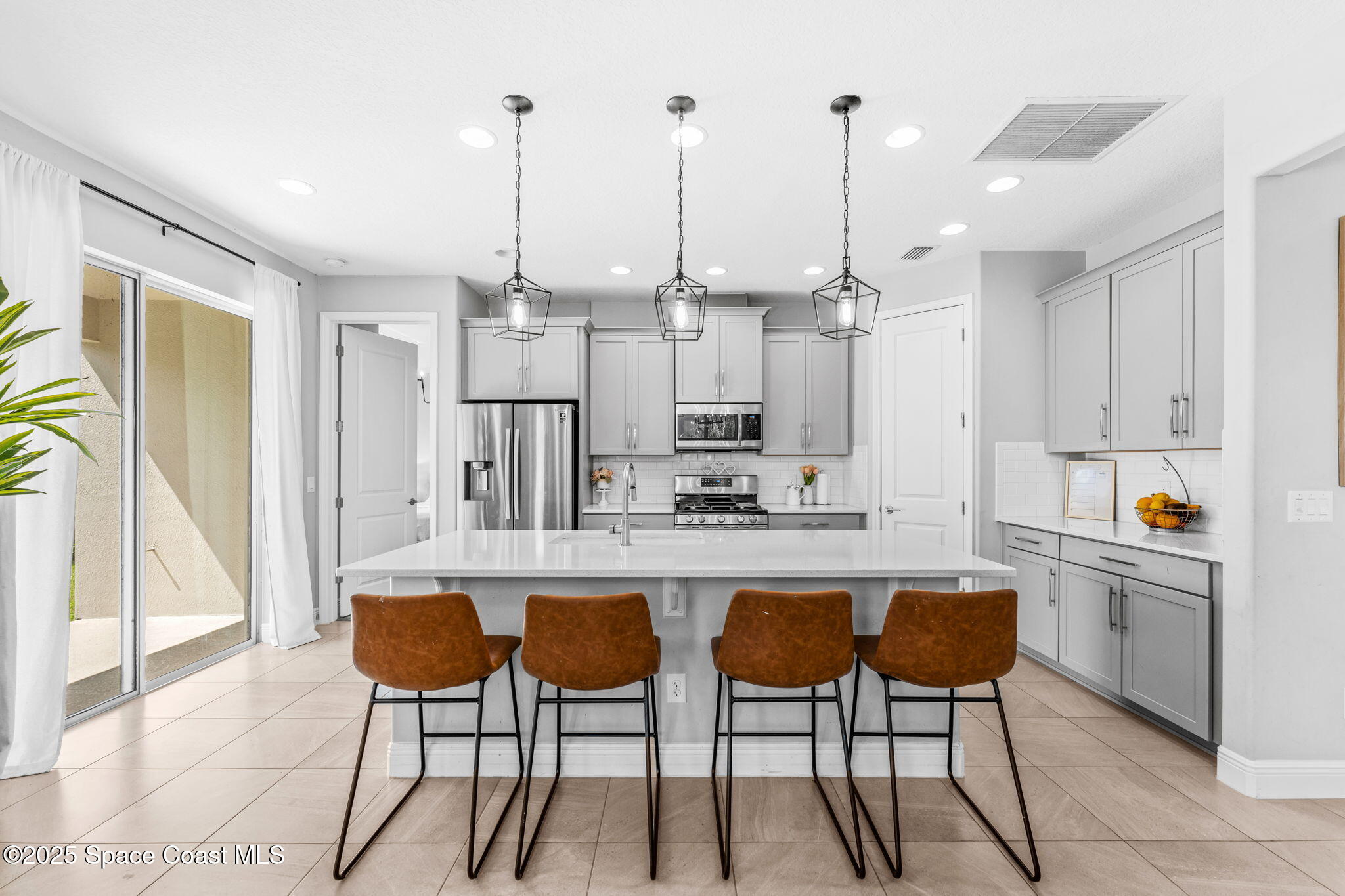 3089 Ribbon Grass Drive Melbourne, FL 32940 - Photo 5 of 57 a kitchen with stainless steel appliances kitchen island granite countertop a table chairs and a refrigerator