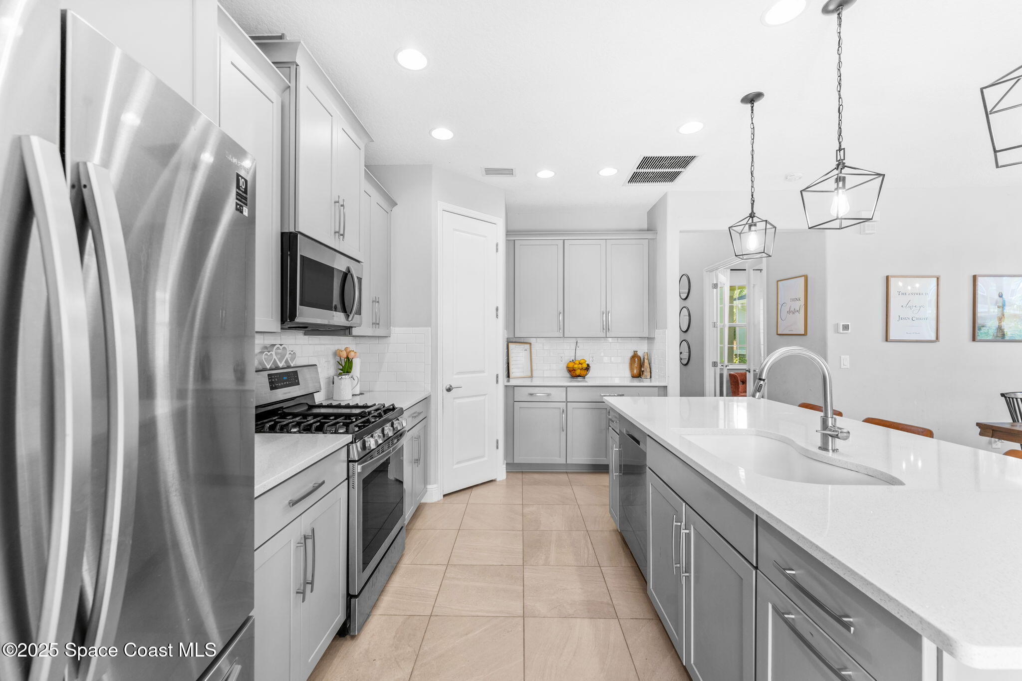 3089 Ribbon Grass Drive Melbourne, FL 32940 - Photo 7 of 57 a large kitchen with stainless steel appliances a sink a stove a refrigerator a center island a stove and a sink