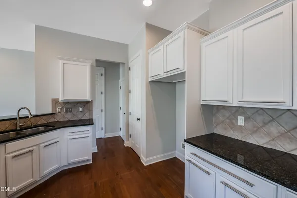 a kitchen with granite countertop white cabinets and a sink