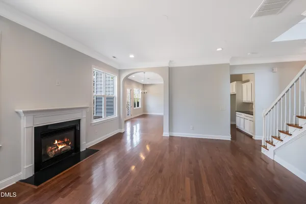 a view of an empty room with wooden floor fireplace and a window