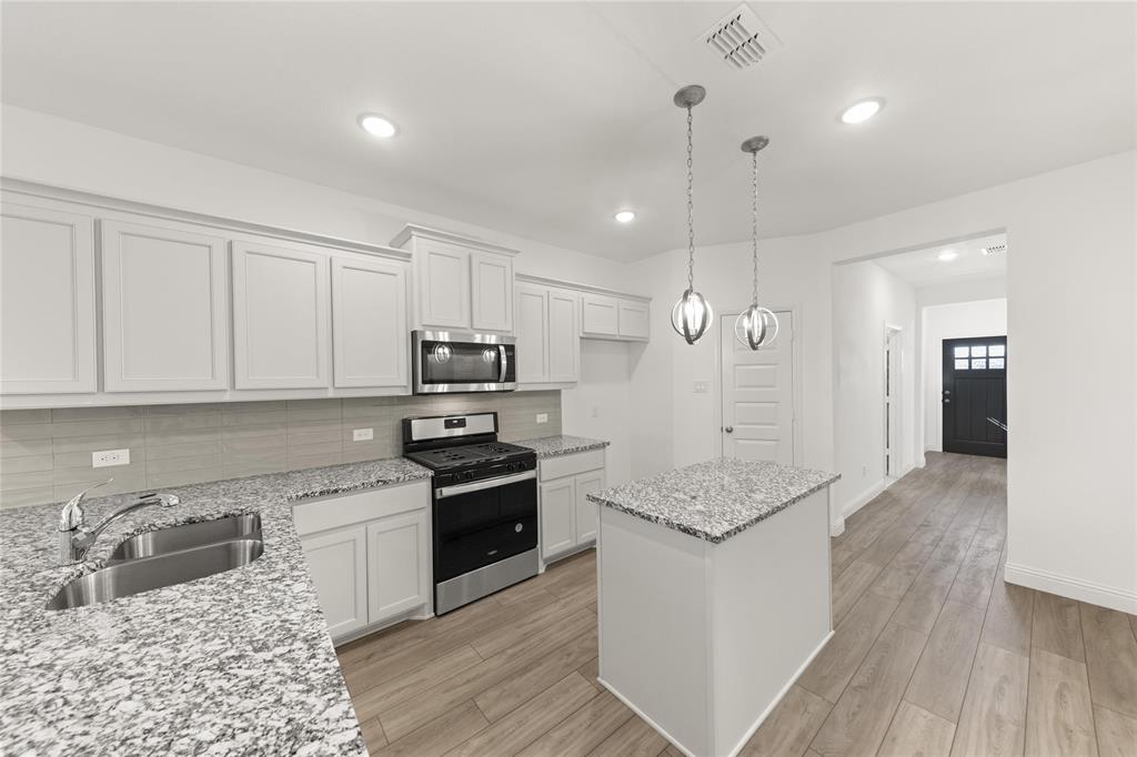 322 Boston Drive Princeton, TX 75407 - Photo 2 of 18 a kitchen with stainless steel appliances granite countertop a refrigerator a sink dishwasher a stove and white countertops with wooden floor