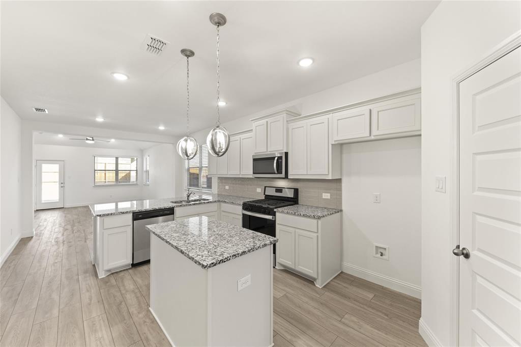 322 Boston Drive Princeton, TX 75407 - Photo 3 of 18 a kitchen with a center island wooden floor and stainless steel appliances