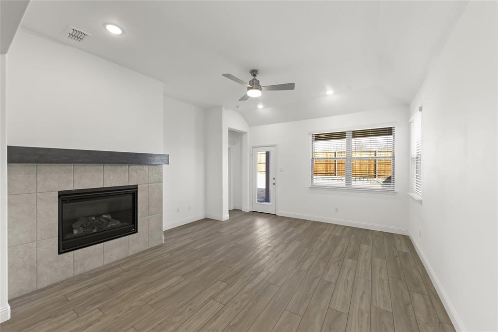 322 Boston Drive Princeton, TX 75407 - Photo 7 of 18 an empty room with wooden floor fireplace and windows