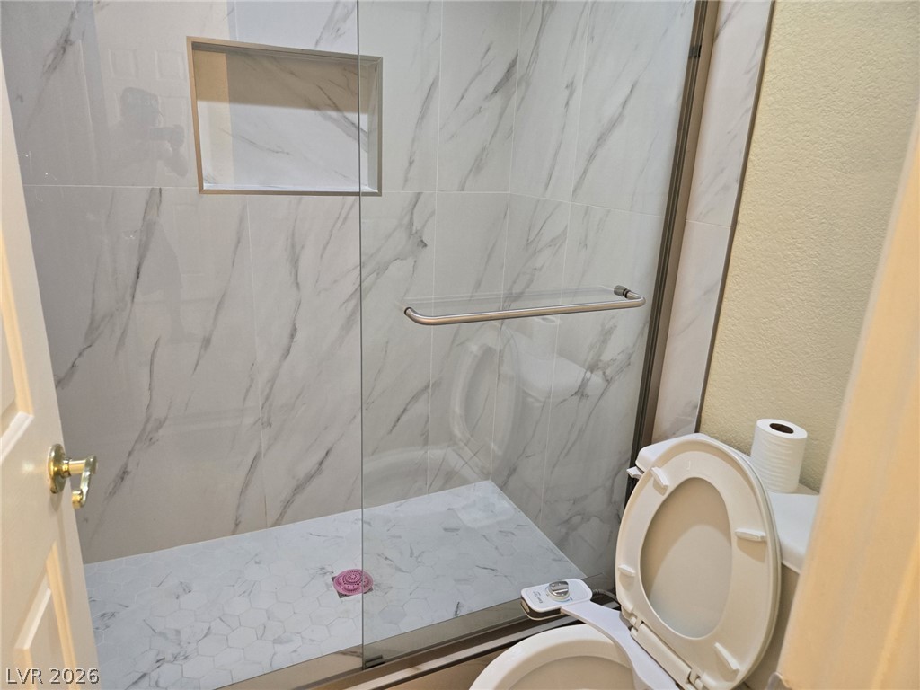 8417 San Ramon Drive Las Vegas, NV 89147 - Photo 29 of 33 Elegant walk-in shower features marble-look tiling and a seamless glass enclosure.