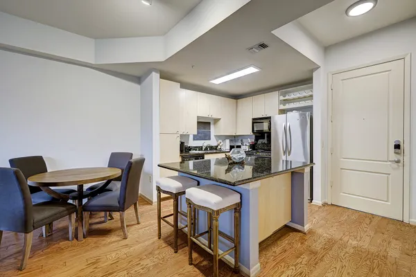 a kitchen with stainless steel appliances granite countertop a stove refrigerator and chairs