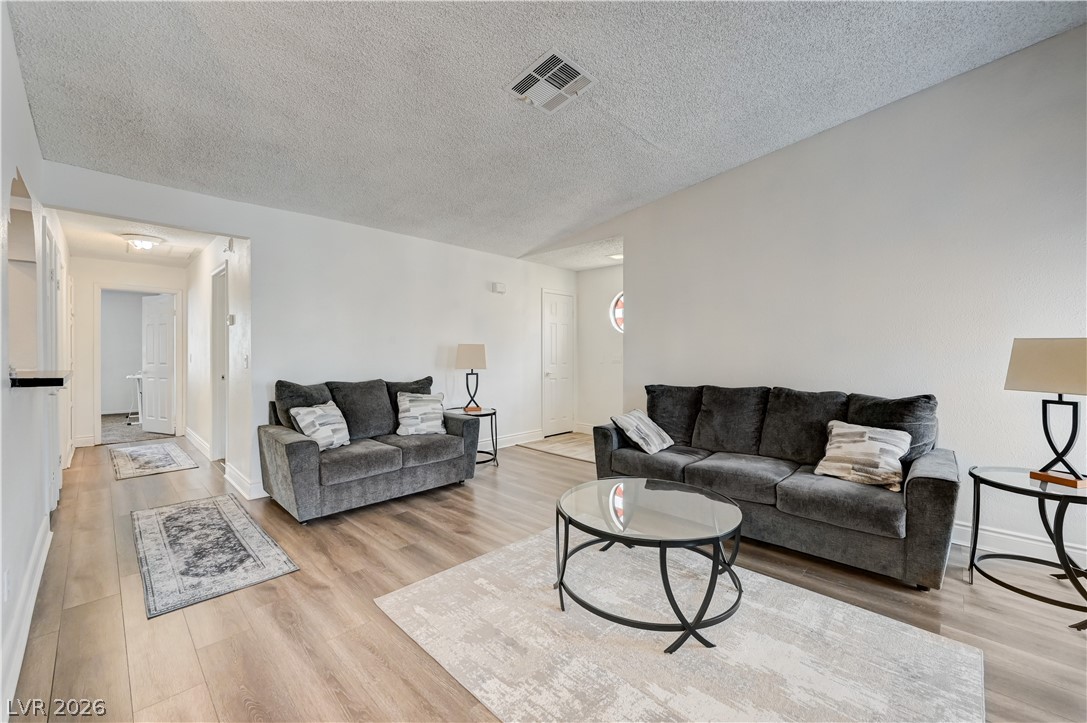 1751 East Reno Avenue, Unit 228 Las Vegas, NV 89119 - Photo 6 of 39 Natural light illuminates this inviting living space, featuring rich hardwood flooring throughout.
