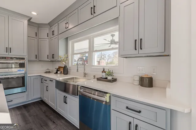 a view of an empty room and kitchen with wooden floor and windows