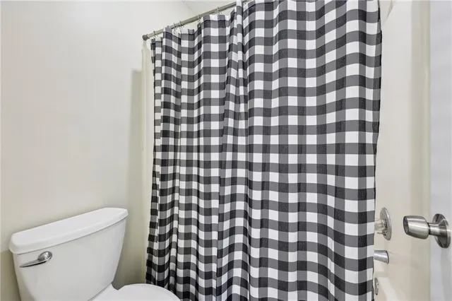 a bathroom with a toilet and a shower curtain