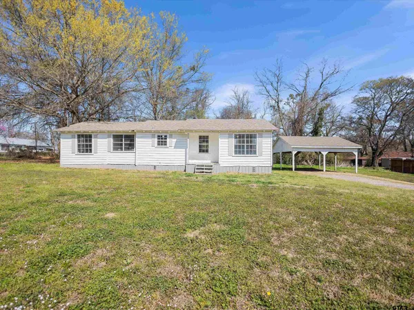 a front view of a house with garden and trees