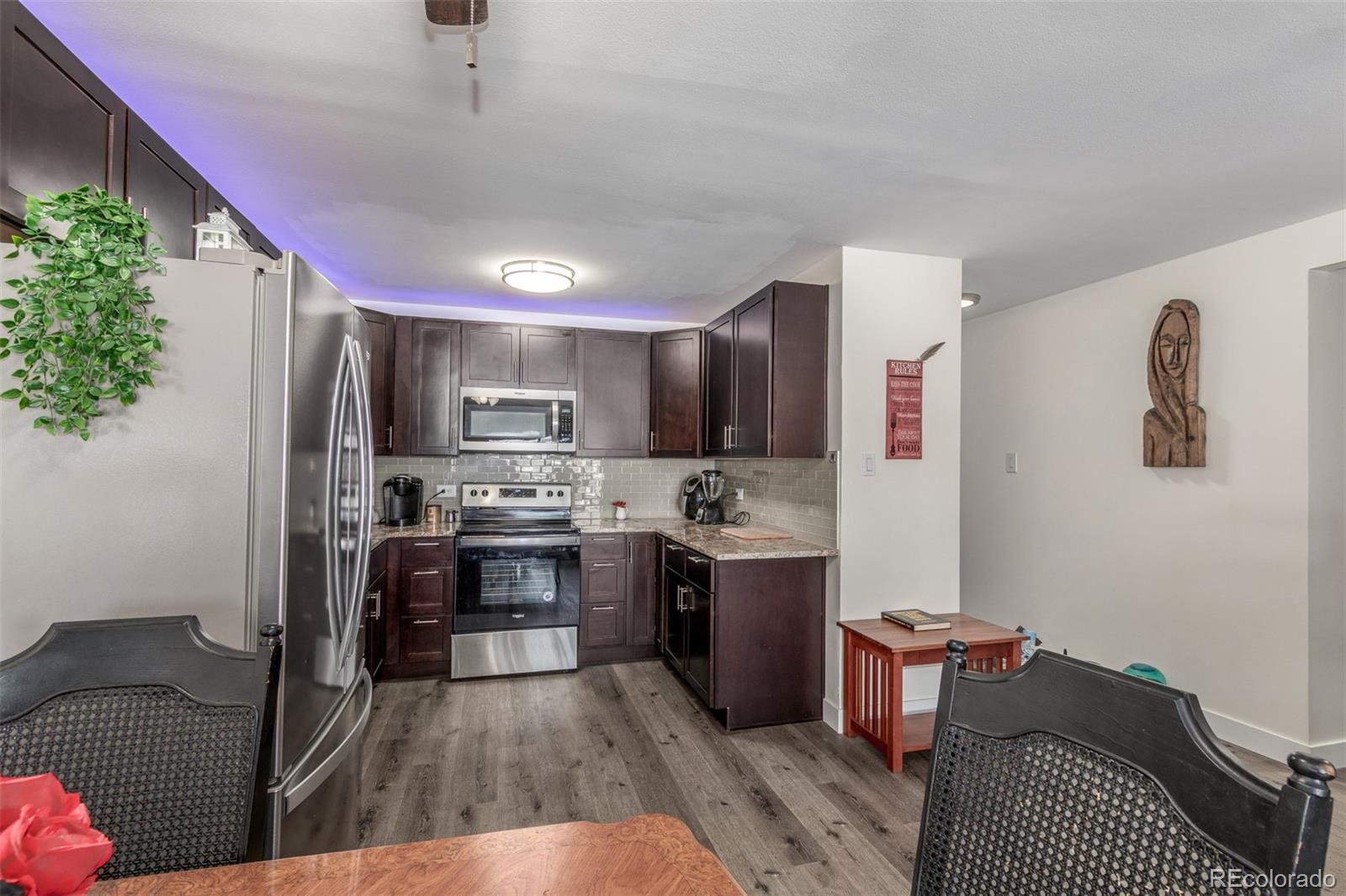 725 South Clinton Street, Unit 7B Denver, CO 80247 - Photo 14 of 29 a kitchen with stainless steel appliances granite countertop a refrigerator a sink dishwasher a dining table and chairs with wooden floor