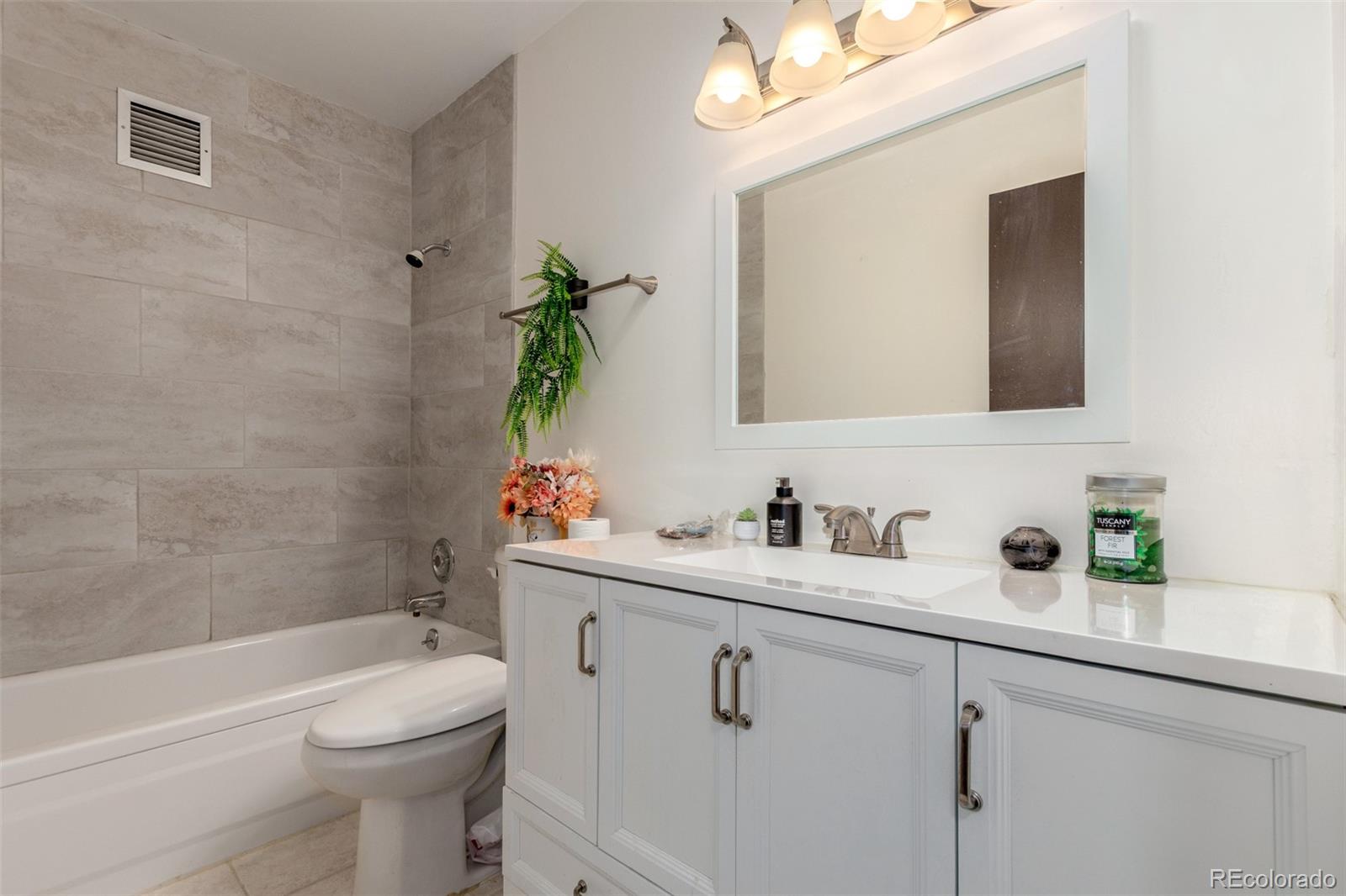 725 South Clinton Street, Unit 7B Denver, CO 80247 - Photo 25 of 29 a bathroom with a toilet a sink a tub and mirror