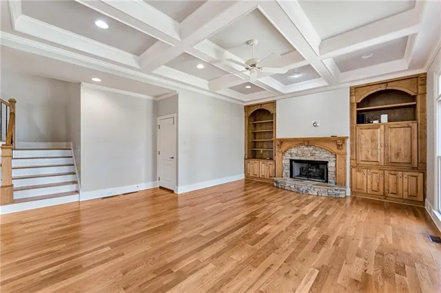 an empty room with wooden floor fireplace and windows