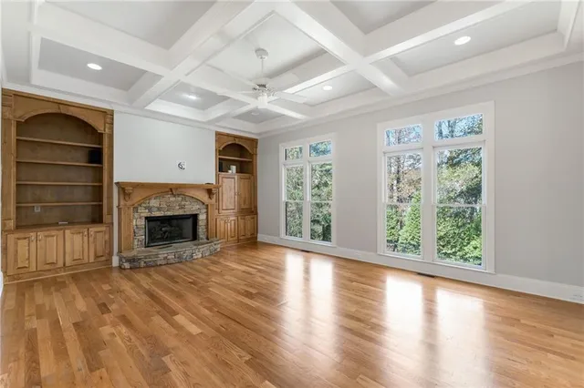 an empty room with windows a fireplace and wooden floor