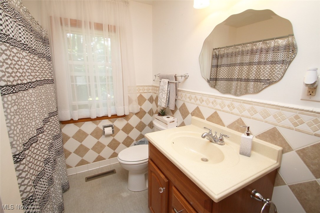 2802 South Ridge Road East Kingsville, OH 44048 - Photo 17 of 42 Full bathroom featuring wainscoting, tile walls, vanity, and tile patterned floors
