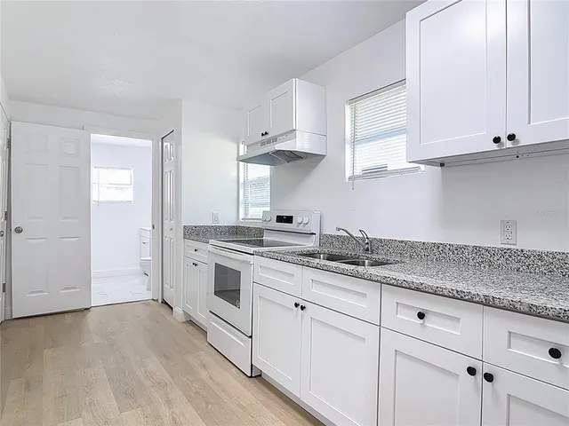 a kitchen with granite countertop white cabinets and white stainless steel appliances
