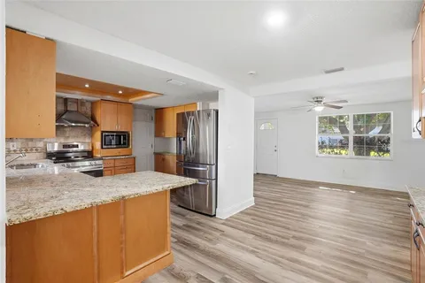 a kitchen with stainless steel appliances granite countertop a refrigerator a sink and wooden cabinets