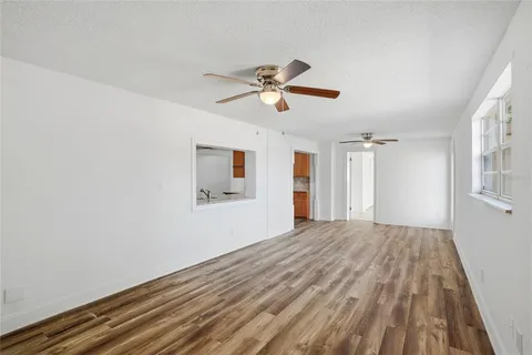 a view of empty room with wooden floor and fan