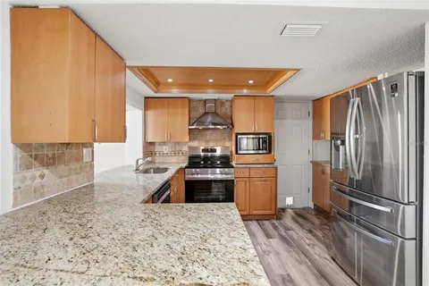 a kitchen with stainless steel appliances kitchen island granite countertop a refrigerator and a sink