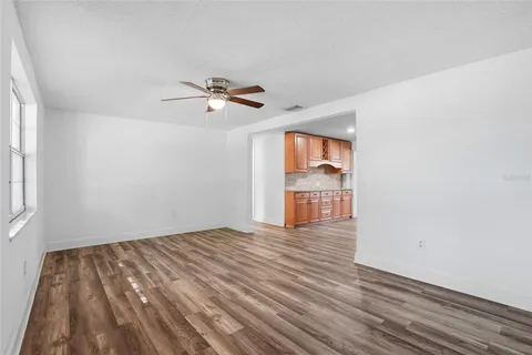 a view of empty room with wooden floor and ceiling fan
