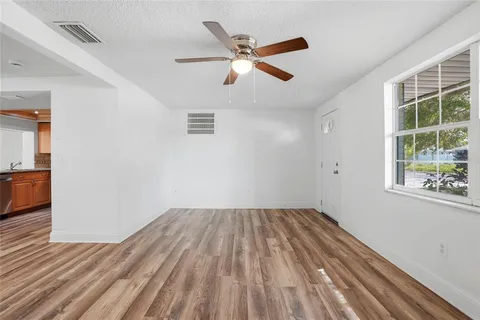 a view of empty room with wooden floor and fan