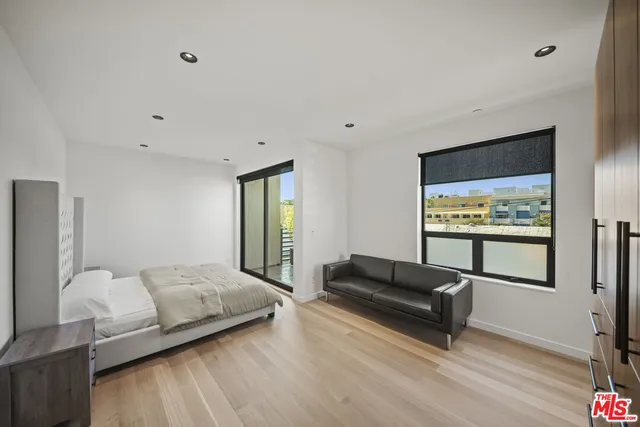 a bedroom with a bed and large windows