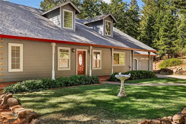 a front view of a house with garden and trees