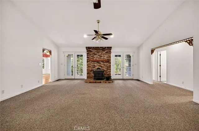 an empty room with windows chandelier fan and windows