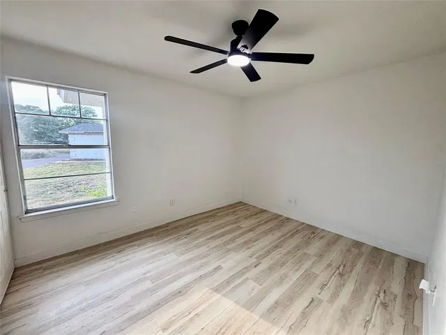 a view of empty room with wooden floor and window