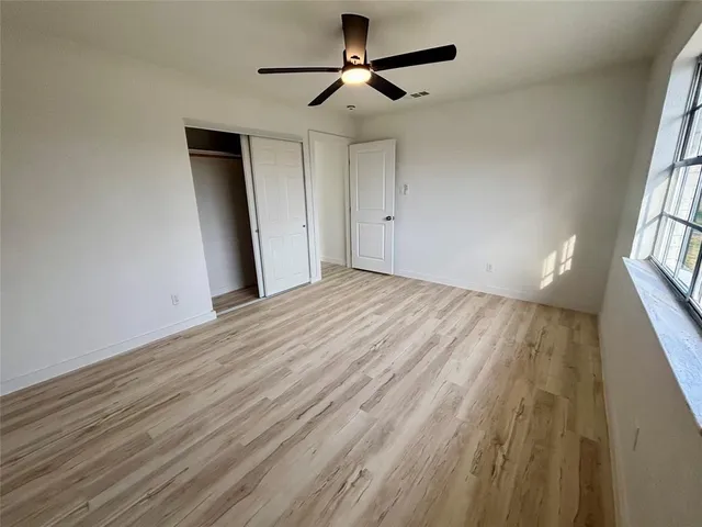a view of empty room with wooden floor and fan
