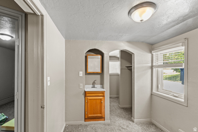 661 East 600 North Logan, UT 84321 - Photo 14 of 15 Compact space featuring a single-sink vanity with wood-finish cabinetry, a wall-mounted medicine cabinet, and arched alcoves