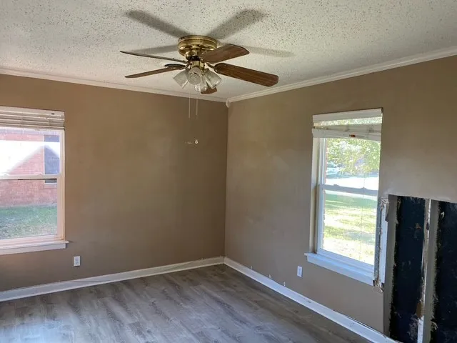 an empty room with windows and fan