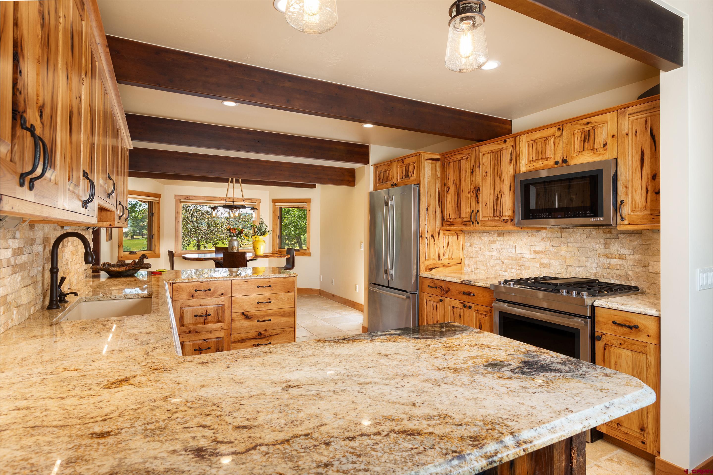 378 Colonial Drive Hesperus, CO 81326 - Photo 12 of 34 a kitchen with stainless steel appliances granite countertop a stove top oven a sink a dining table and chairs with wooden floor
