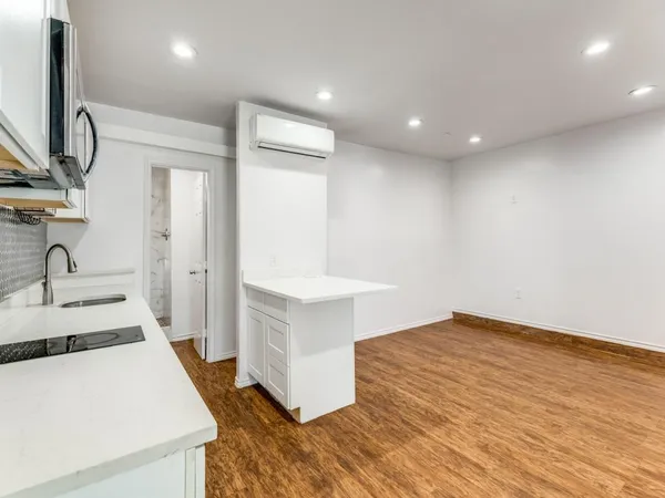 a view of a kitchen with kitchen island a sink wooden floor and a living room