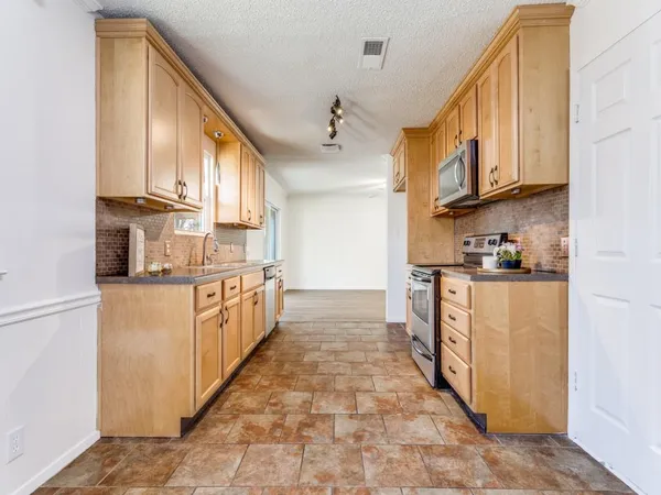 a kitchen with stainless steel appliances granite countertop a refrigerator a stove and a sink