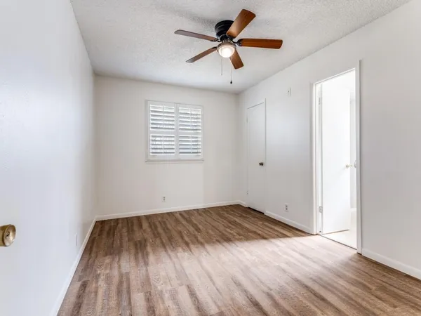 an empty room with wooden floor ceiling fan and windows