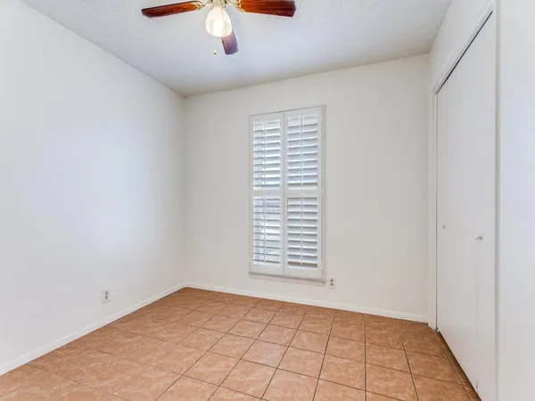 an empty room with chandelier fan and windows
