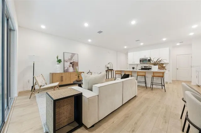 a living room with stainless steel appliances furniture and a kitchen view