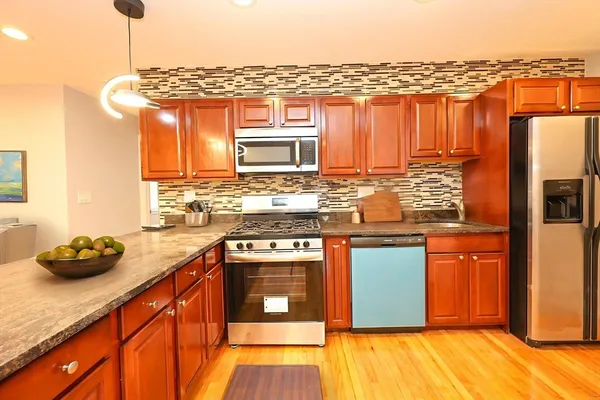 a kitchen with stainless steel appliances granite countertop a stove a sink and a refrigerator