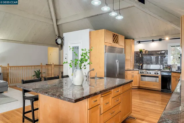 a kitchen with stainless steel appliances granite countertop a sink a stove and a refrigerator