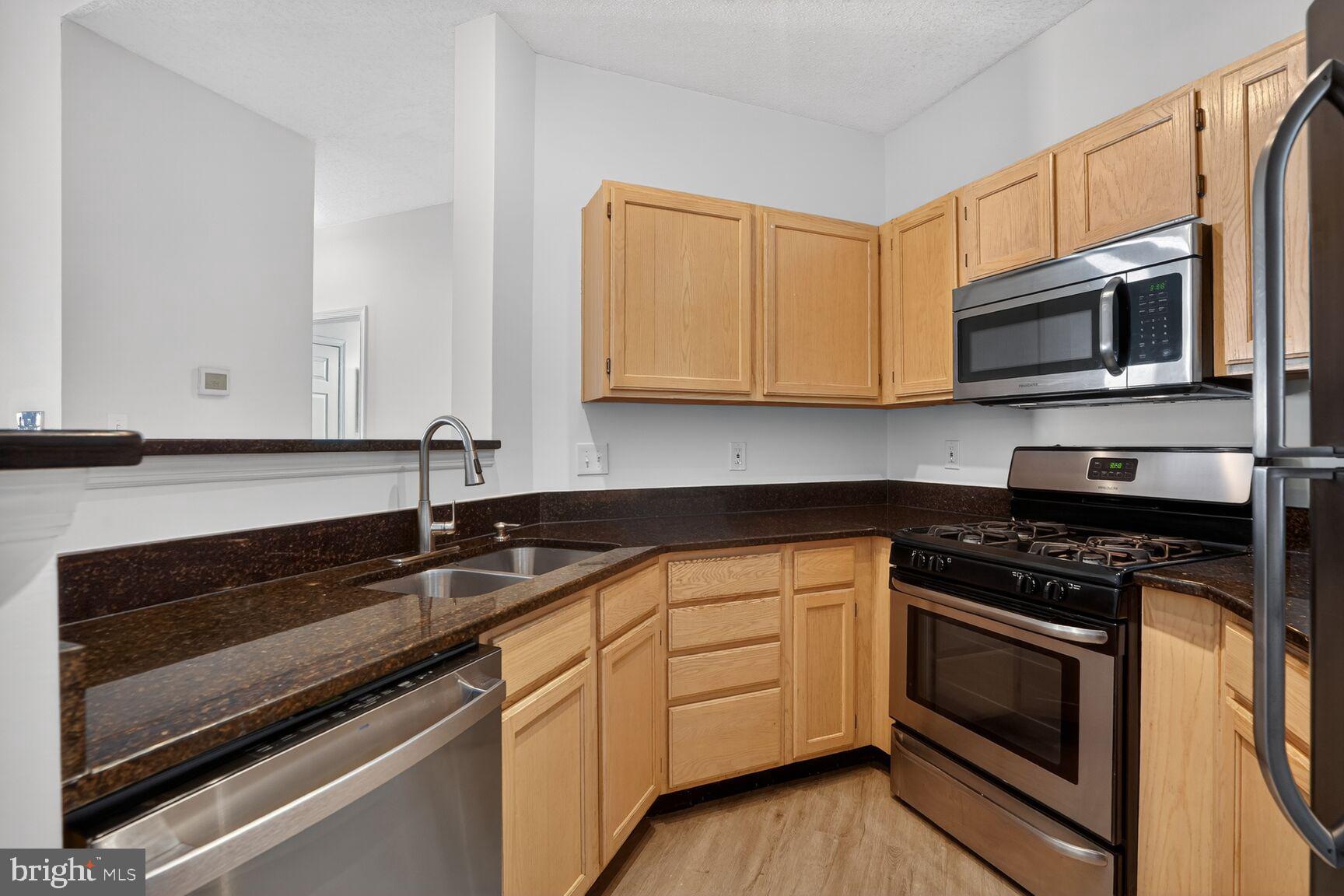 14322 Climbing Rose Way, Unit 306 Centreville, VA 20121 - Photo 11 of 35 a kitchen with granite countertop cabinets stainless steel appliances and a sink