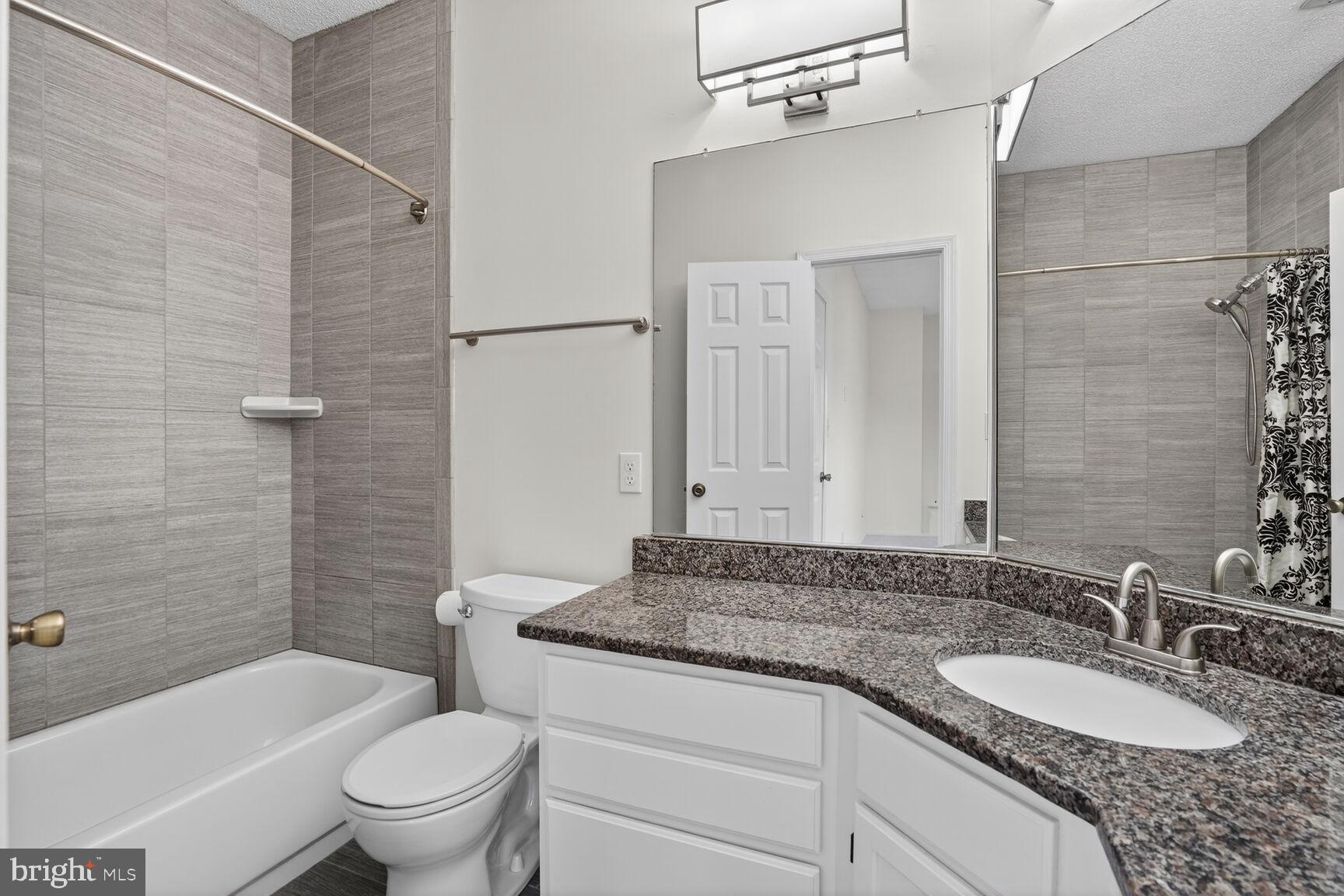 14322 Climbing Rose Way, Unit 306 Centreville, VA 20121 - Photo 16 of 35 a bathroom with a granite countertop sink a toilet a mirror and shower