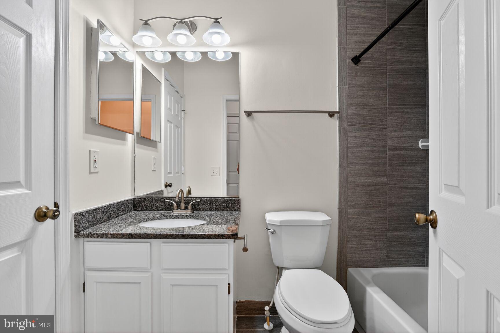 14322 Climbing Rose Way, Unit 306 Centreville, VA 20121 - Photo 20 of 35 a bathroom with a granite countertop sink vanity mirror and toilet