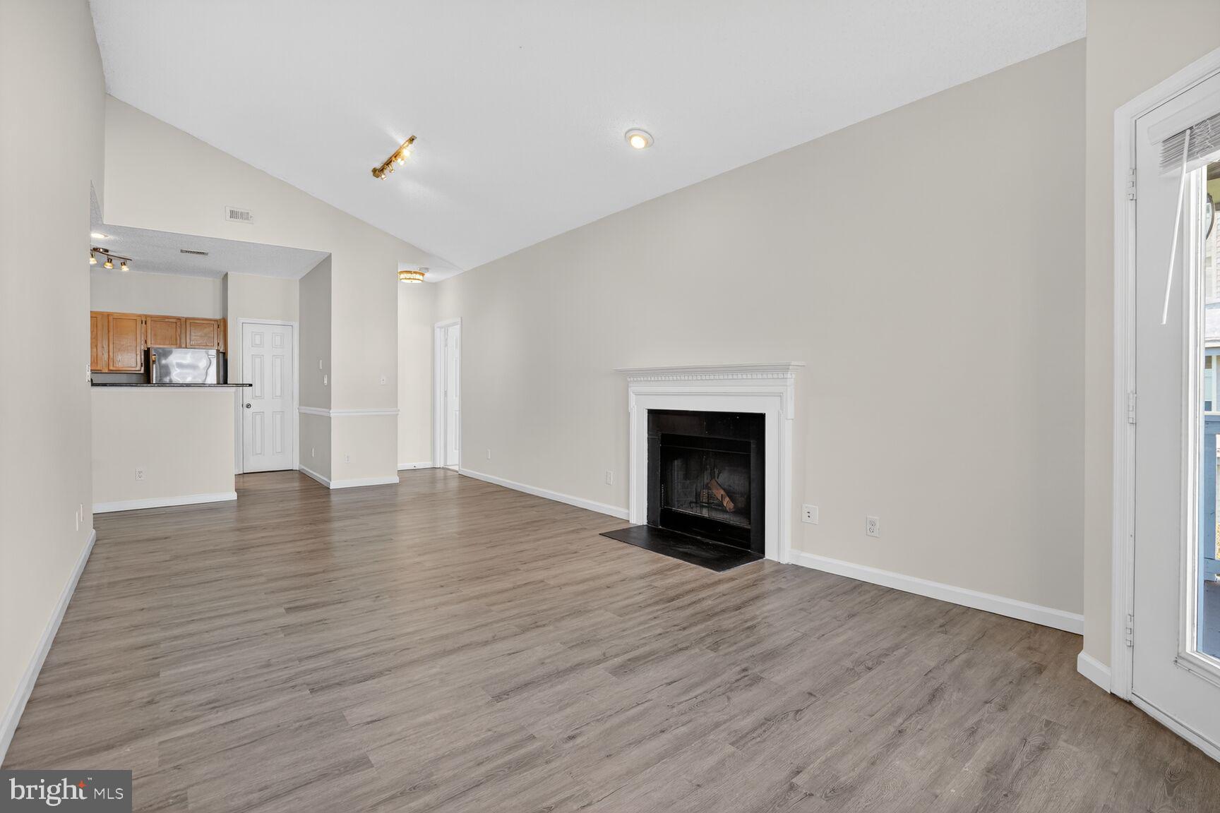 14322 Climbing Rose Way, Unit 306 Centreville, VA 20121 - Photo 4 of 35 an empty room with wooden floor and fireplace